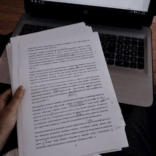 Translator holding a printed script while working on a literary translation.